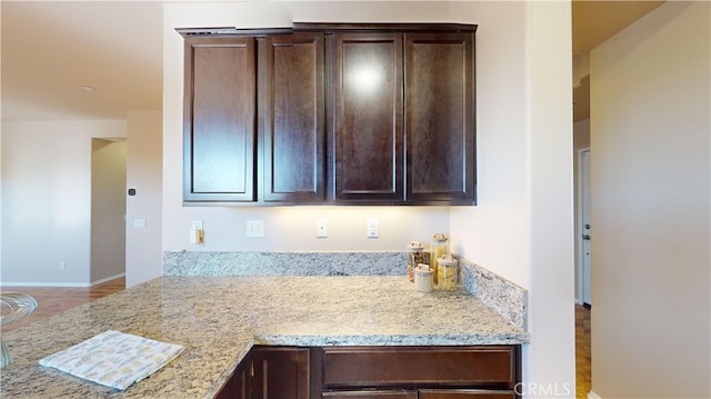 kitchen featuring light stone counters and dark brown cabinets