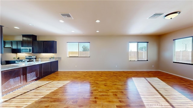 kitchen featuring appliances with stainless steel finishes, sink, light stone counters, and hardwood / wood-style flooring