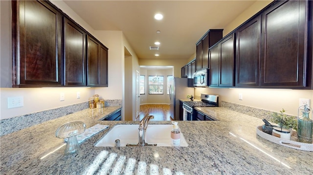 kitchen featuring dark brown cabinets, sink, light stone counters, and stainless steel appliances