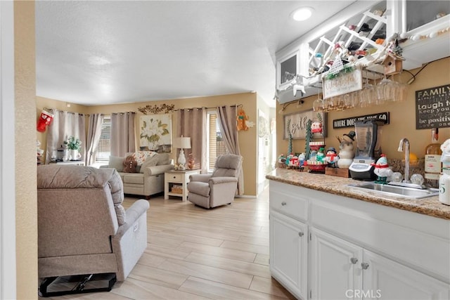 kitchen featuring light wood-type flooring, white cabinetry, and sink