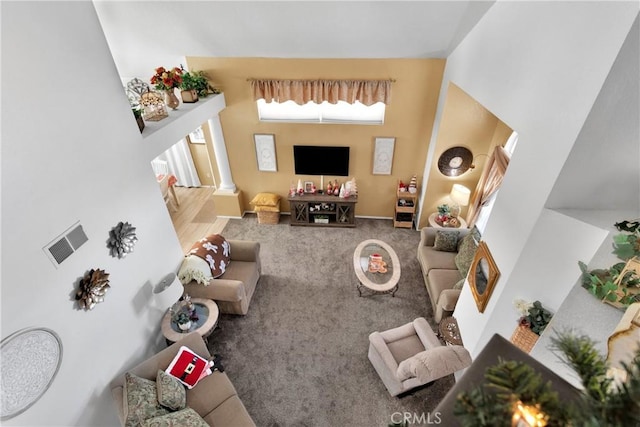 living room featuring carpet flooring, ornate columns, and a towering ceiling