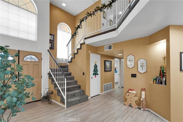 entryway featuring a towering ceiling and light hardwood / wood-style flooring