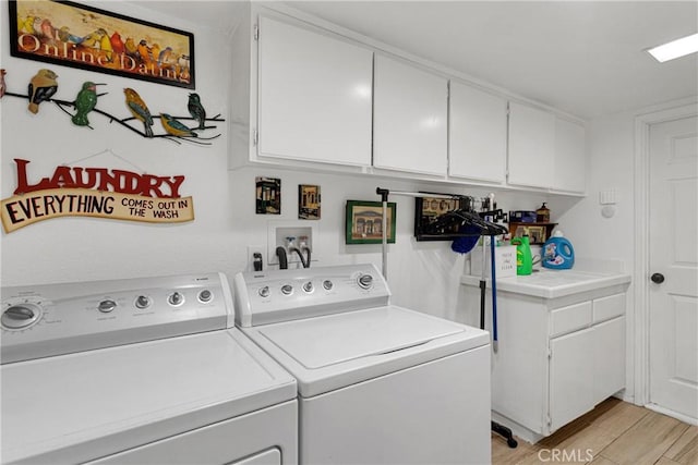 laundry area with washer and clothes dryer, cabinets, and light hardwood / wood-style floors