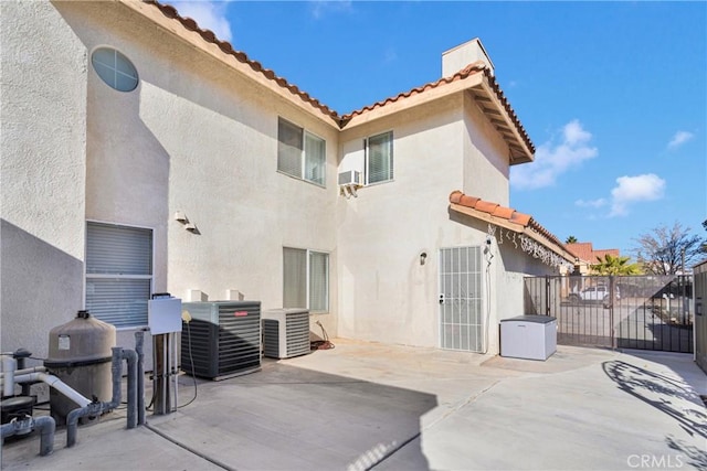 rear view of house with central AC unit and a patio area