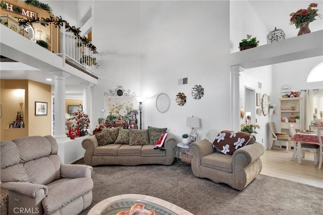 living room with a high ceiling, light hardwood / wood-style floors, and decorative columns