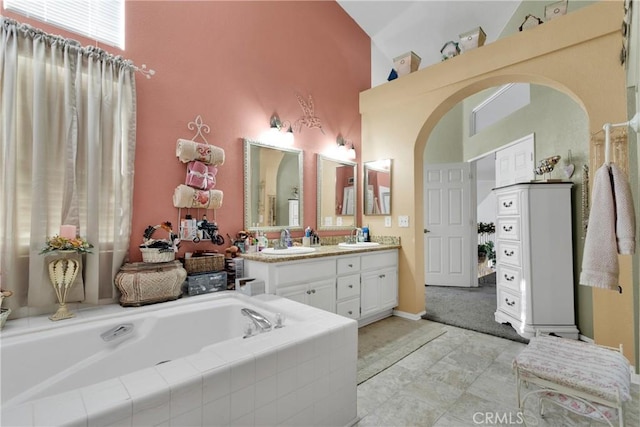 bathroom featuring tiled bath, vanity, tile patterned floors, and high vaulted ceiling