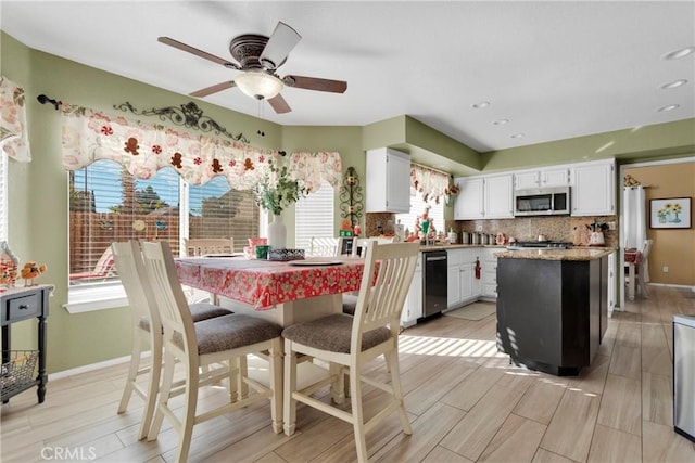 kitchen featuring white cabinetry, a center island, stainless steel appliances, light hardwood / wood-style flooring, and backsplash