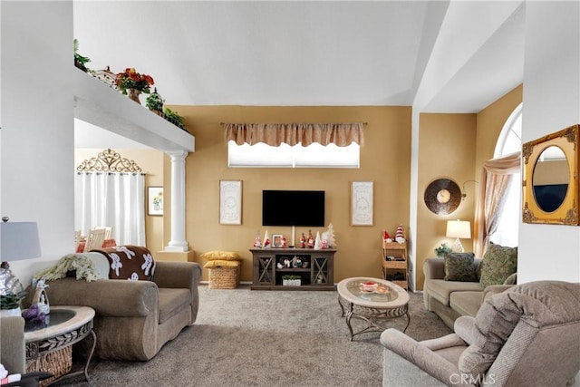 carpeted living room with ornate columns, plenty of natural light, and a high ceiling