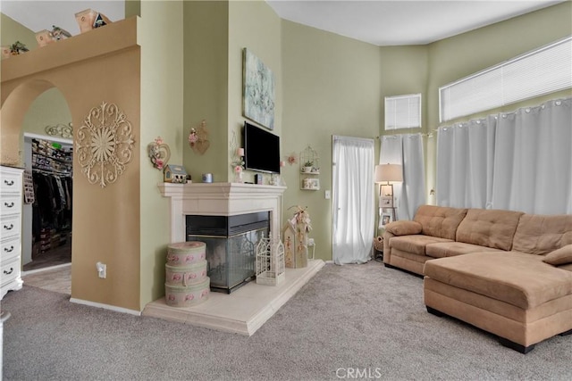 living room with carpet, a towering ceiling, and a multi sided fireplace