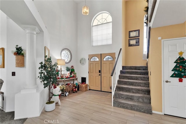 entrance foyer featuring decorative columns, a high ceiling, and light wood-type flooring