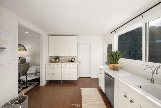 kitchen featuring dishwasher, sink, decorative backsplash, dark hardwood / wood-style flooring, and white cabinetry