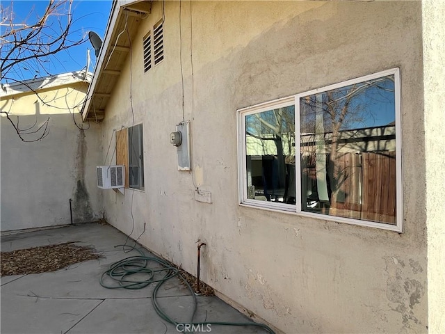 view of home's exterior with a patio area and a wall unit AC