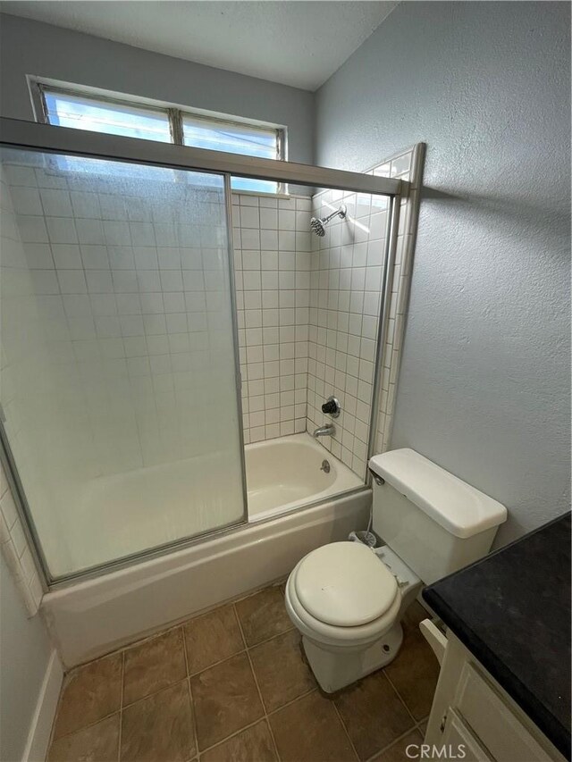 full bathroom featuring tile patterned floors, vanity, toilet, and enclosed tub / shower combo