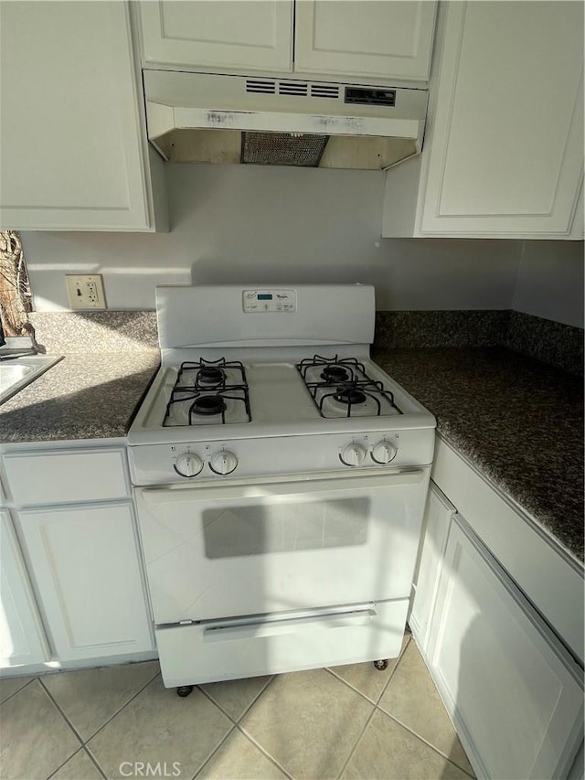 kitchen featuring light tile patterned flooring, white cabinetry, white range with gas cooktop, and dark stone counters