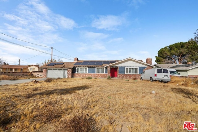 ranch-style house featuring a garage and solar panels