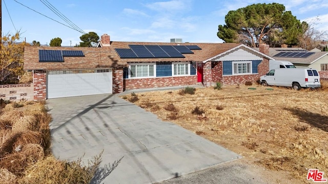 single story home with a garage and solar panels