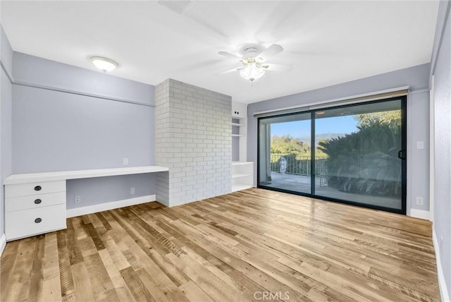 unfurnished living room featuring built in desk, light hardwood / wood-style floors, and ceiling fan