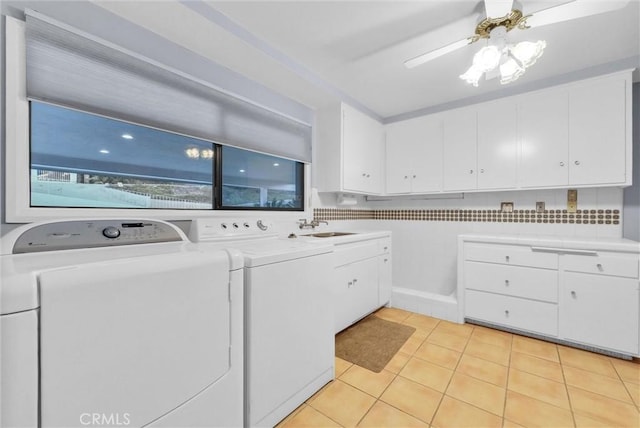 clothes washing area with cabinets, washer and clothes dryer, ceiling fan, sink, and light tile patterned floors