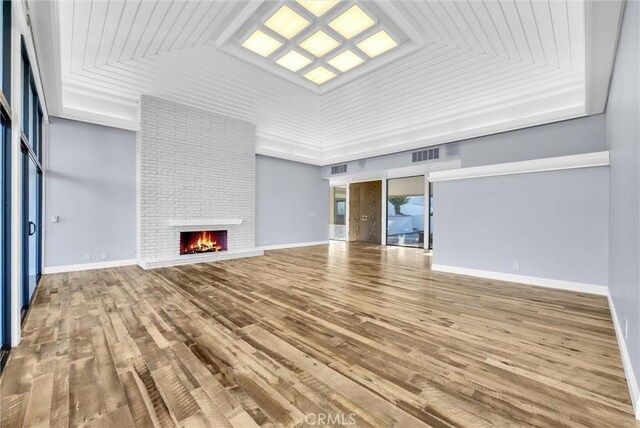 unfurnished living room with wood-type flooring, a brick fireplace, lofted ceiling, and wood ceiling