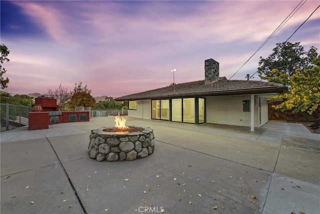 back house at dusk featuring an outdoor fire pit and a patio