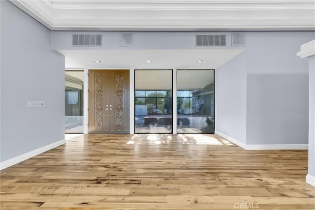 empty room with french doors, a wealth of natural light, and light hardwood / wood-style flooring