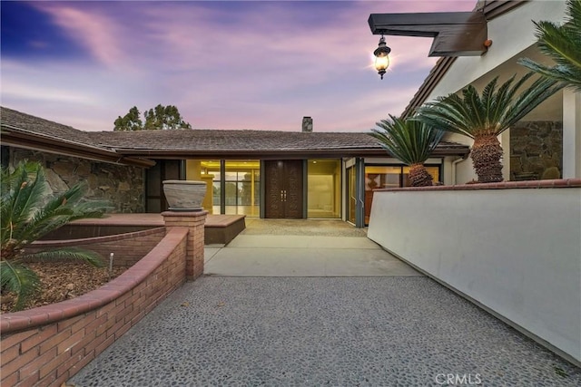 exterior entry at dusk featuring a patio area