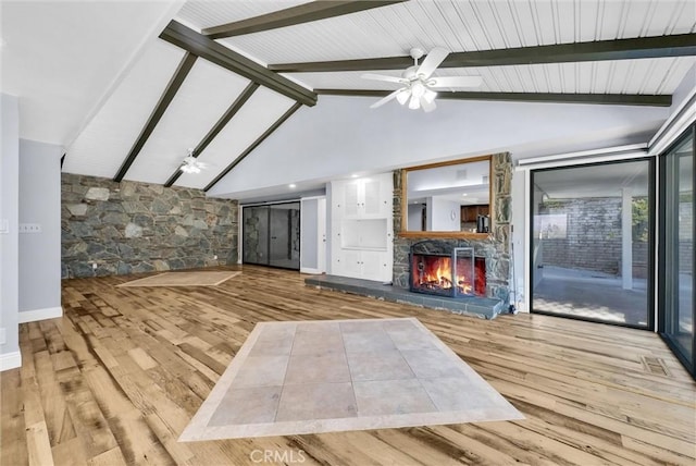 unfurnished living room with a fireplace, light hardwood / wood-style flooring, ceiling fan, and beamed ceiling