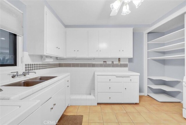 kitchen with white cabinets, decorative backsplash, sink, and light tile patterned flooring