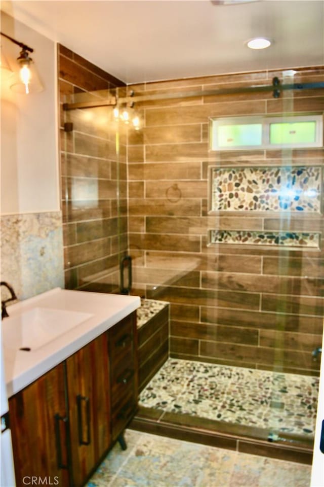 bathroom with vanity, a shower with shower door, and tile walls