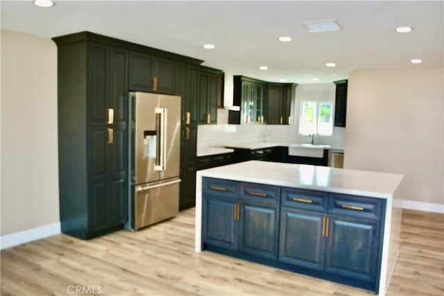 kitchen featuring appliances with stainless steel finishes, wall chimney exhaust hood, sink, a center island, and light hardwood / wood-style floors