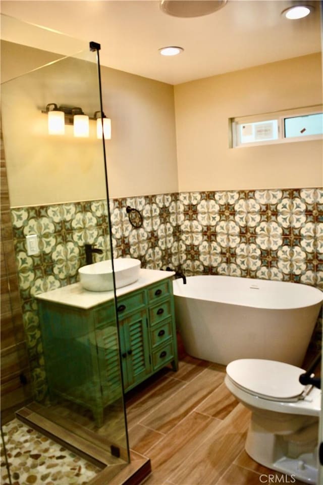 bathroom featuring a tub to relax in, vanity, and toilet