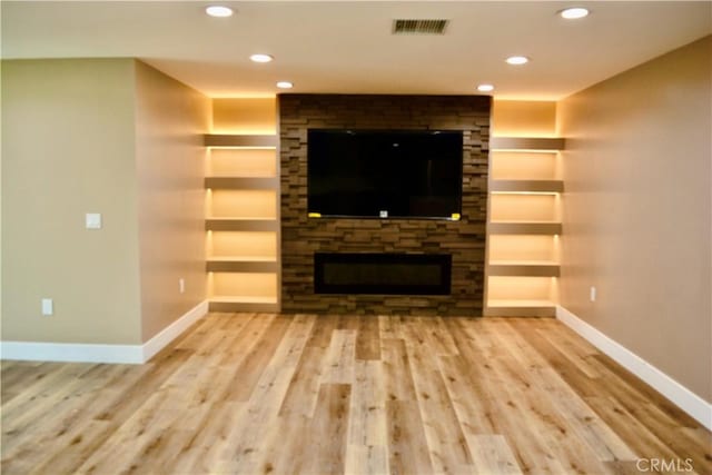 unfurnished living room with hardwood / wood-style floors, built in features, and a fireplace