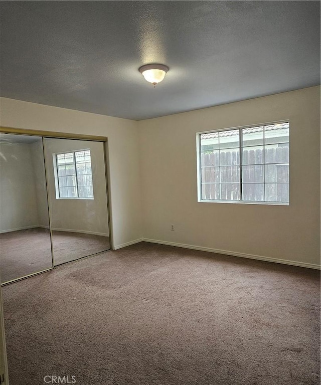 unfurnished bedroom featuring carpet flooring, a textured ceiling, and a closet