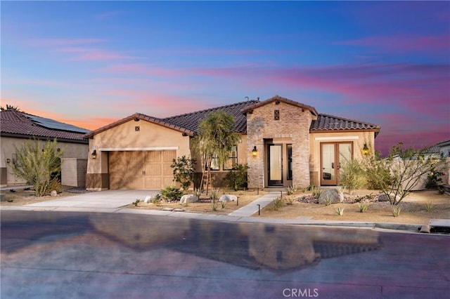 mediterranean / spanish home featuring a garage, concrete driveway, a tiled roof, and stucco siding