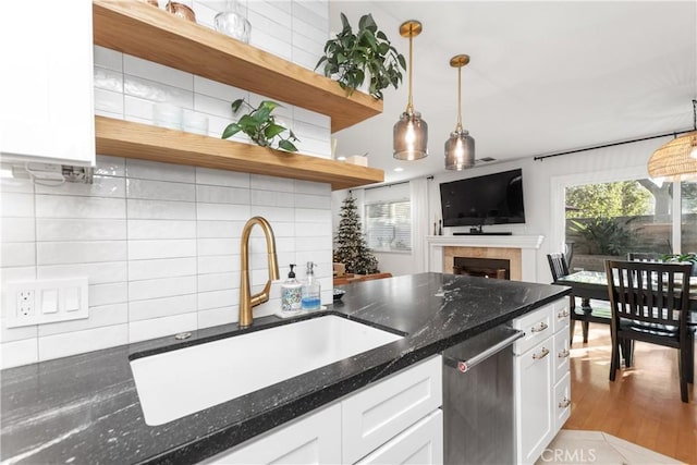 kitchen featuring tasteful backsplash, a tile fireplace, sink, and white cabinets