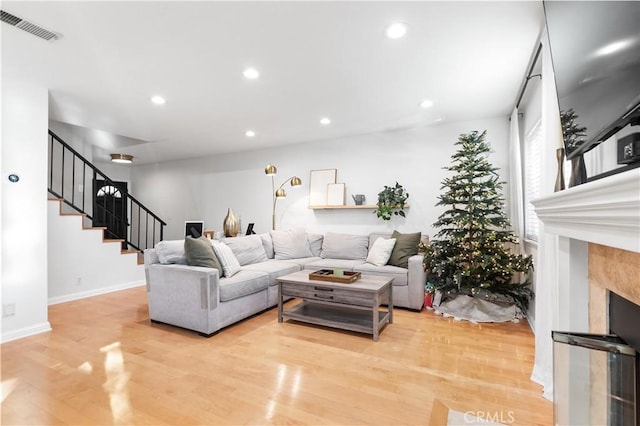 living room with wood-type flooring and a tiled fireplace