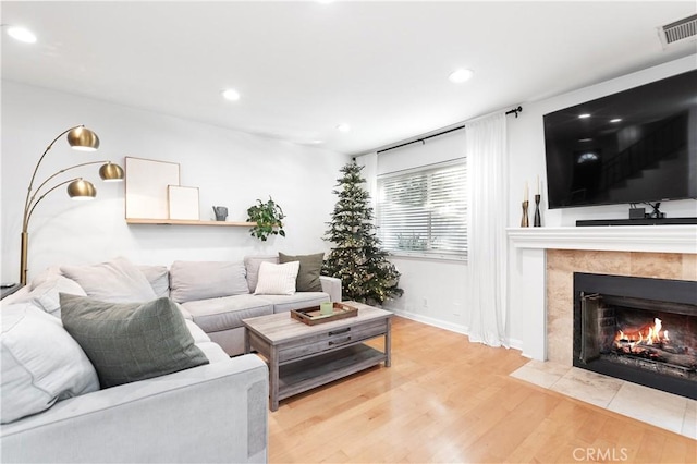 living room featuring light hardwood / wood-style floors and a tiled fireplace