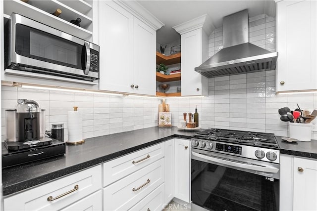 kitchen with decorative backsplash, appliances with stainless steel finishes, white cabinetry, and wall chimney range hood