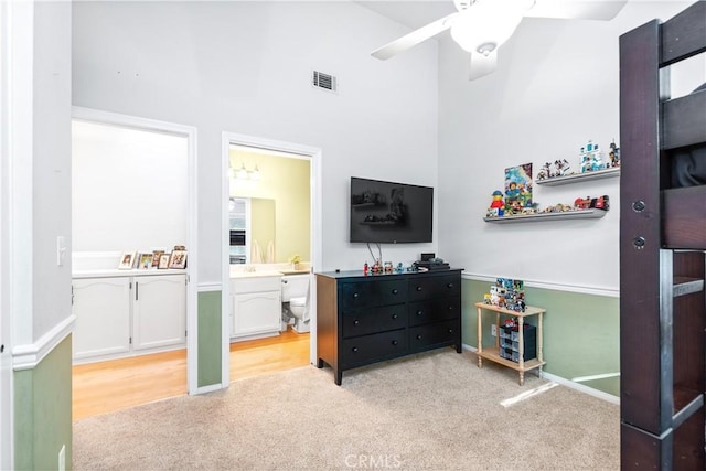 bedroom featuring light carpet, connected bathroom, and ceiling fan