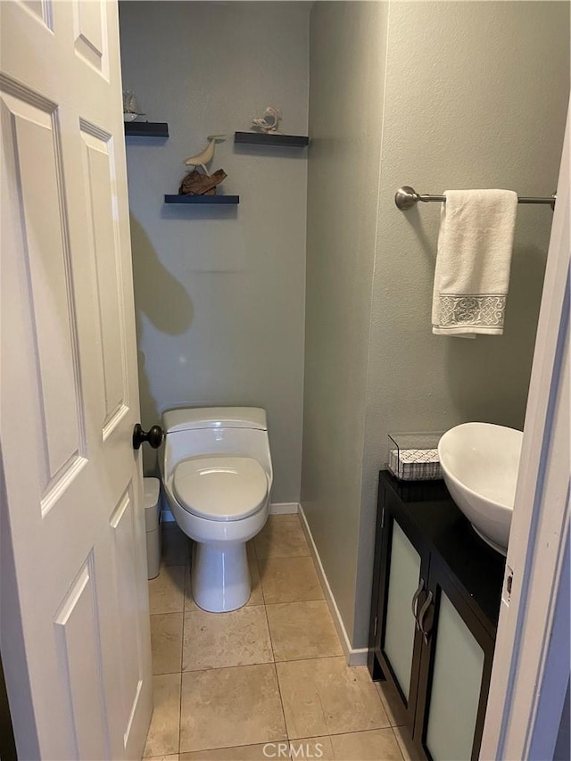 bathroom with toilet, vanity, and tile patterned floors