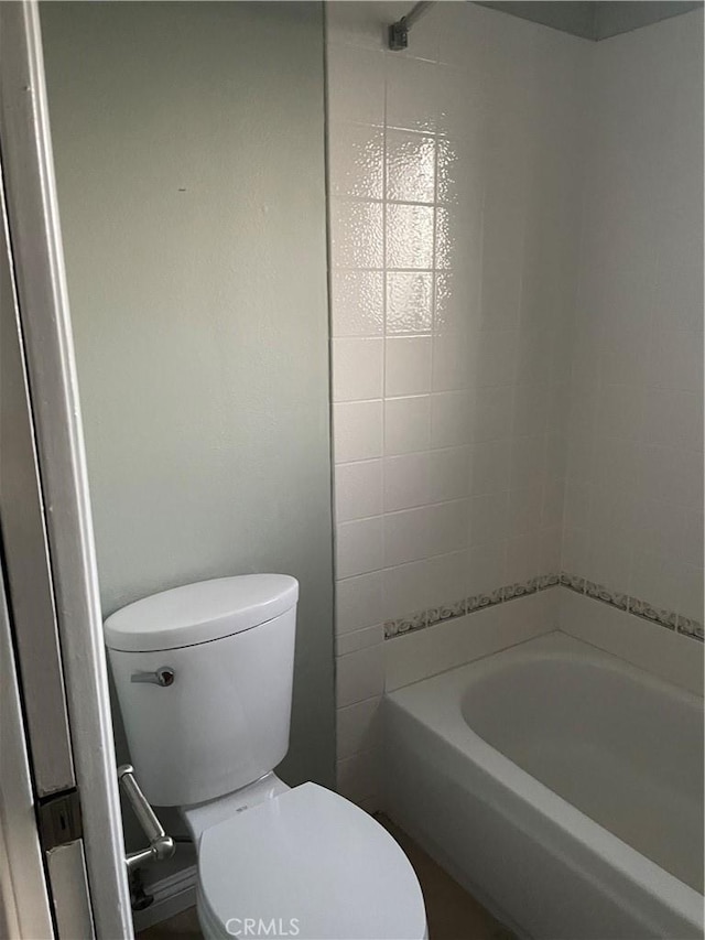 bathroom featuring toilet and tiled shower / bath