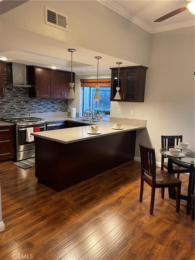 kitchen featuring pendant lighting, sink, dark hardwood / wood-style flooring, kitchen peninsula, and stainless steel range with gas stovetop