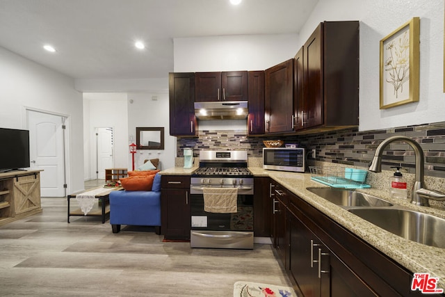 kitchen with sink, decorative backsplash, light wood-type flooring, light stone counters, and stainless steel appliances