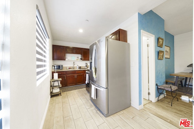 kitchen with appliances with stainless steel finishes, light wood-type flooring, and sink