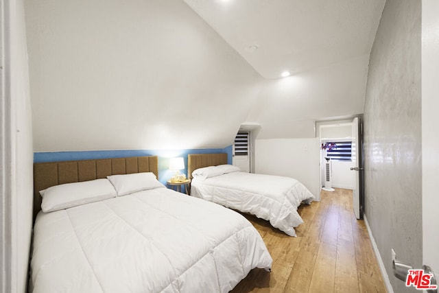 bedroom with wood-type flooring and vaulted ceiling