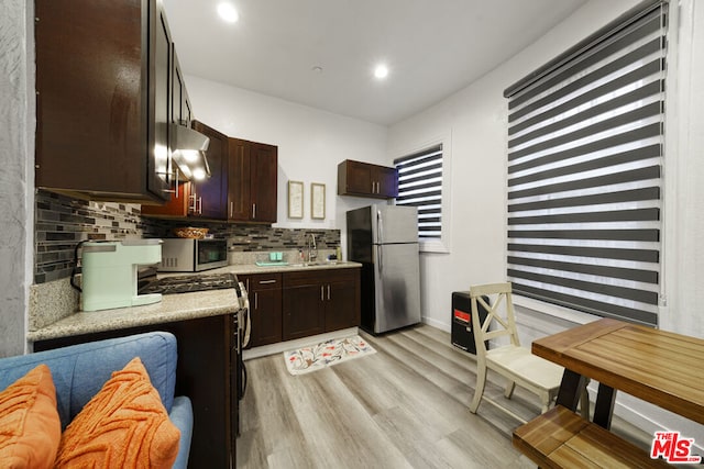 kitchen with backsplash, sink, light hardwood / wood-style floors, and appliances with stainless steel finishes