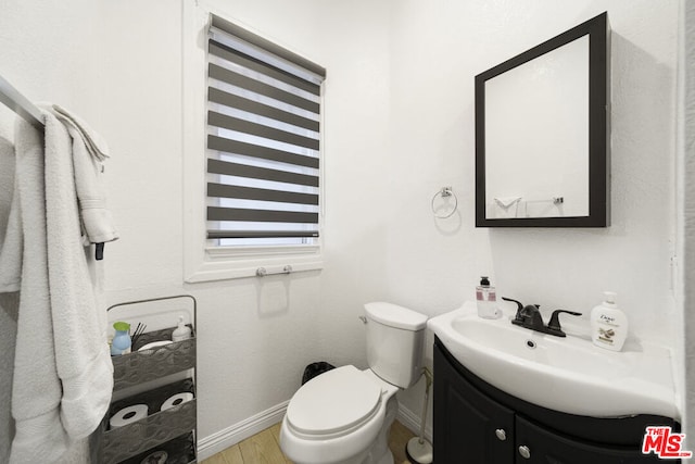 bathroom with wood-type flooring, vanity, and toilet