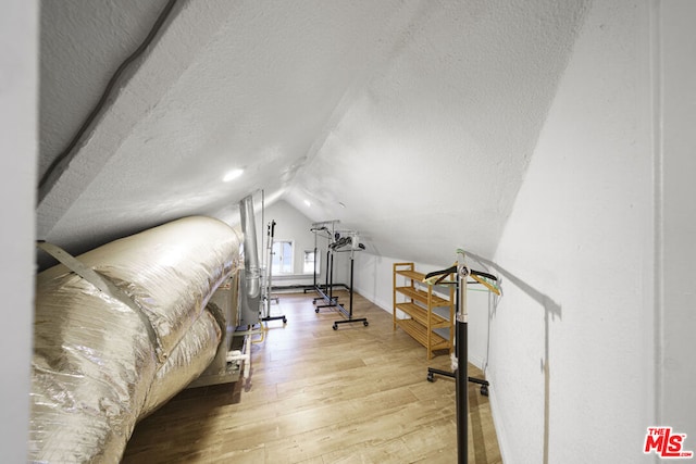 bedroom with a textured ceiling, hardwood / wood-style floors, and vaulted ceiling