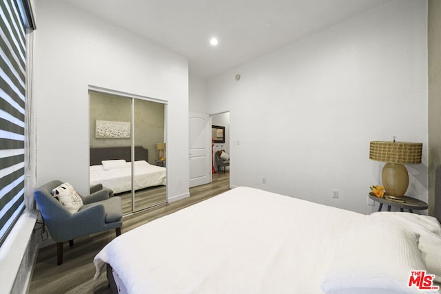 bedroom featuring a high ceiling, hardwood / wood-style flooring, and a closet