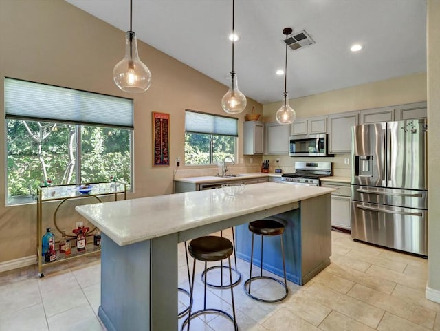 kitchen featuring gray cabinetry, hanging light fixtures, a kitchen island, and appliances with stainless steel finishes